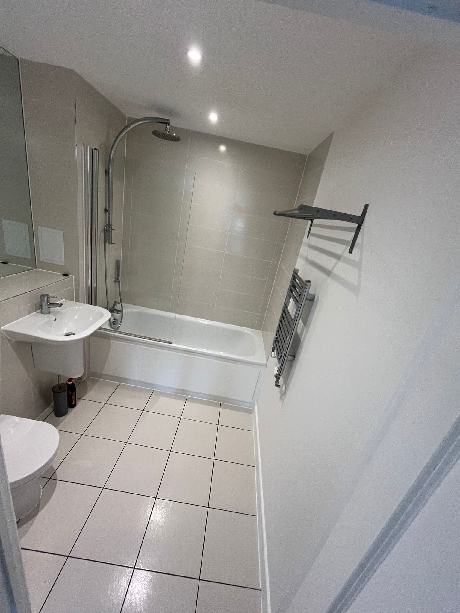 Sparkling clean bathroom with bath, rainfall shower and white tiled floor after cleaning