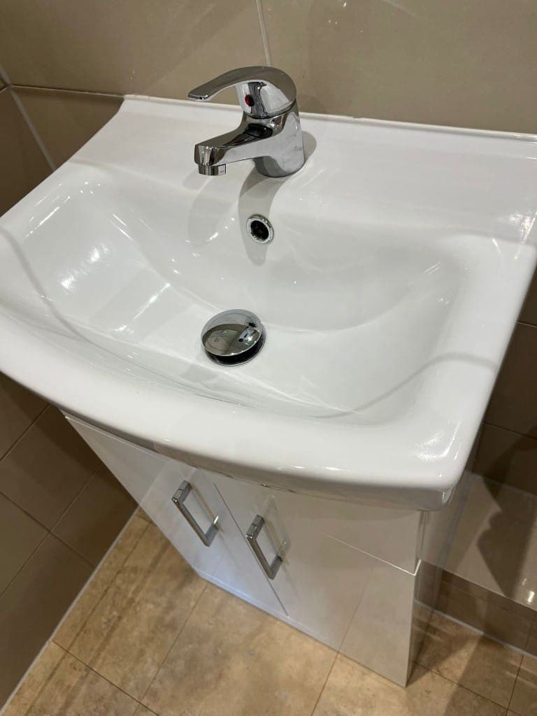 Spotless white bathroom basin and gloss vanity unit with a polished chrome mixer tap after an end of tenancy clean