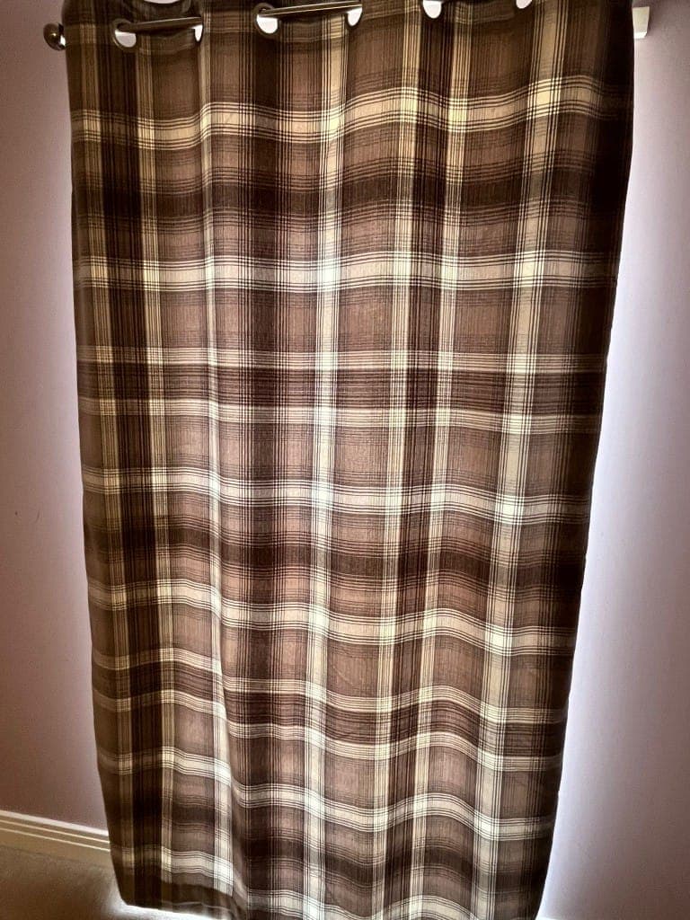 Freshly cleaned brown tartan check eyelet curtains hanging neatly after professional curtain cleaning