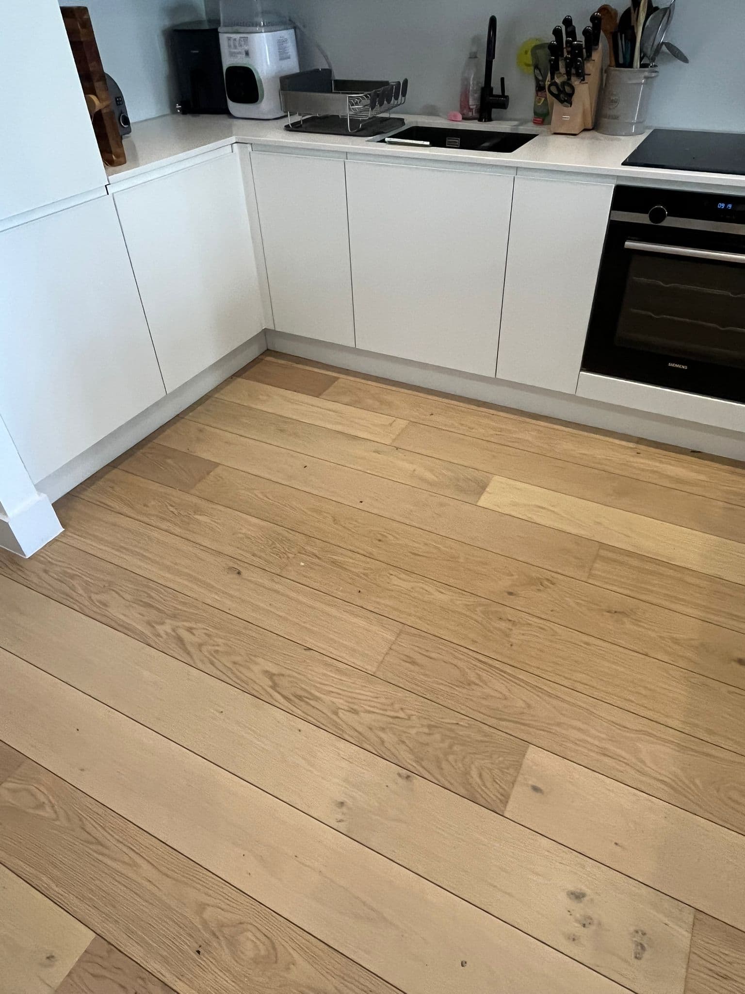 Clean white kitchen with freshly cleaned engineered wood flooring