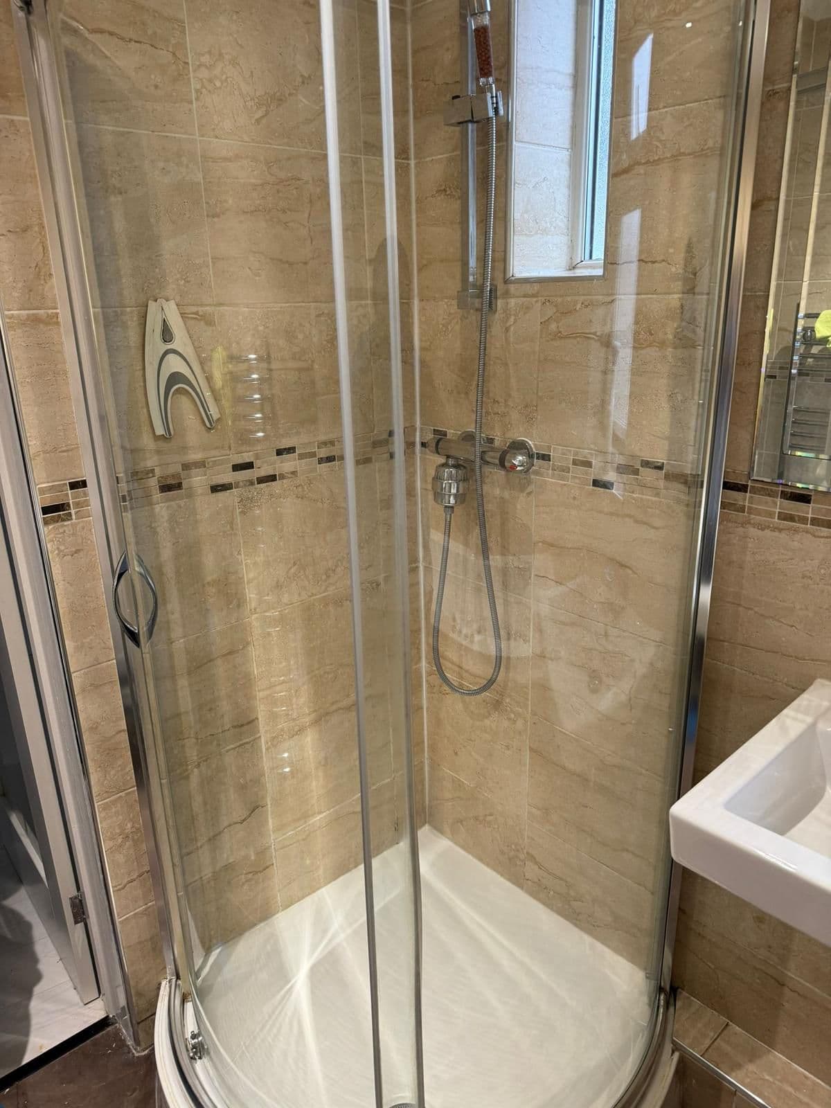 The same shower enclosure with crystal-clear glass and clean tiles after cleaning