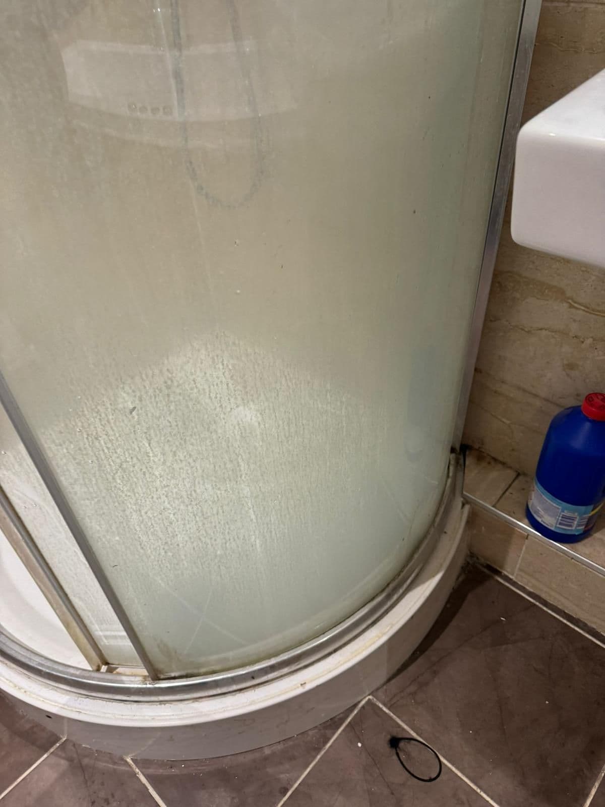 Shower glass covered in limescale and soap scum before cleaning