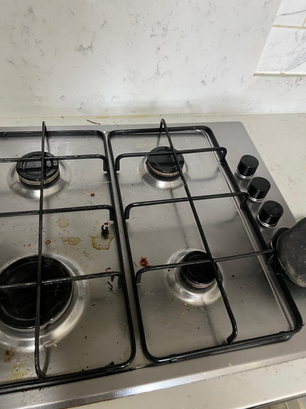 Gas hob with food spills and grease around the burners before cleaning