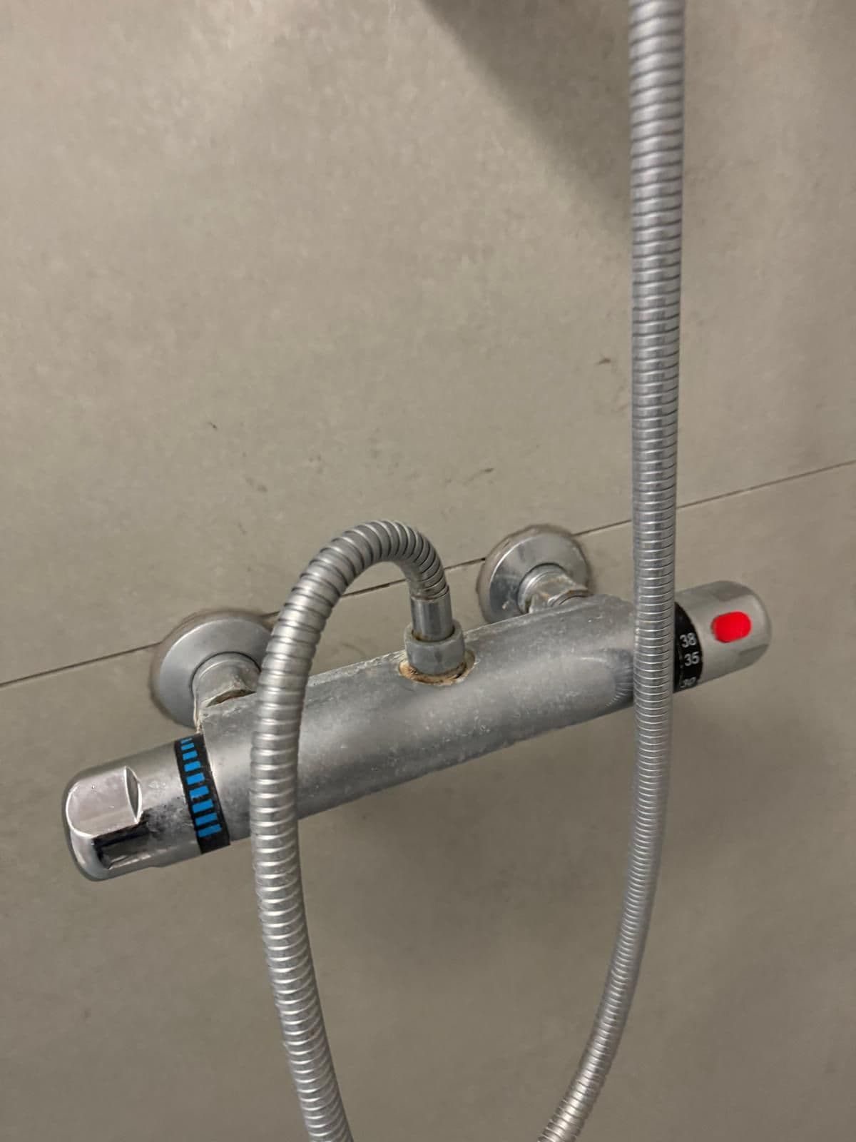 Chrome shower mixer bar coated in limescale and water marks before cleaning