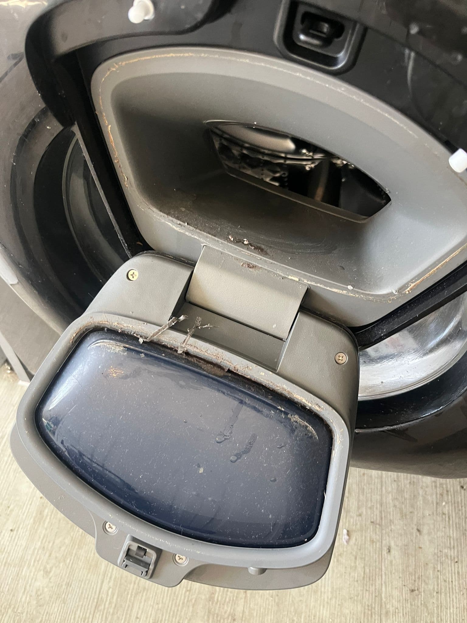 Grime and residue built up around a washing machine door and rubber seal before cleaning